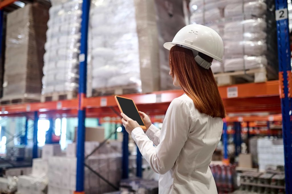 Woman inspecting a warehouse using inventory management software on a tablet