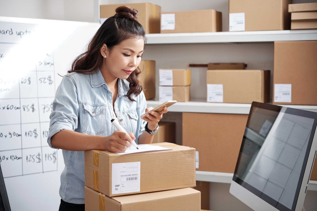 Woman writing on a package, linked to inventory management software